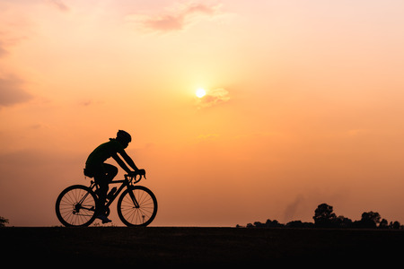 Silhouette of cyclist in motion on the background of beautiful sunsetの写真素材