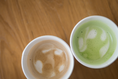 Hot Cappuccino coffee and hot green tea in paper cup on a wooden table, top viewの写真素材