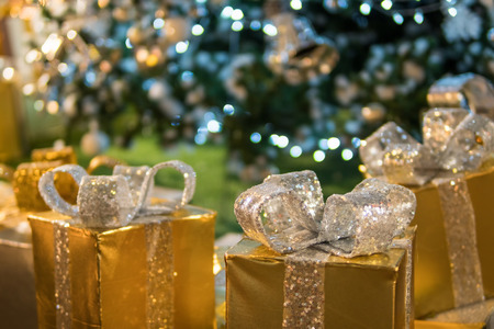 Christmas gifts boxes and ornaments on Christmas tree with light bokehの写真素材