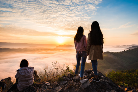 Aerial view Young woman standing on top of mountain to enjoy the mist in winter morning, travel and freedom conceptの写真素材