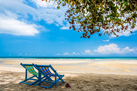 Beach chair under the tree at empty sand beach with blue sea and blue sky background. Summer Vacation Travel and Holiday conceptの写真素材