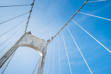 The wire metal rope bridge on blue sky backgroundの写真素材