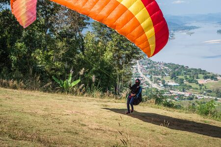Person practicing paragliding flying sport over the Mekong River, outdoor adventureの写真素材