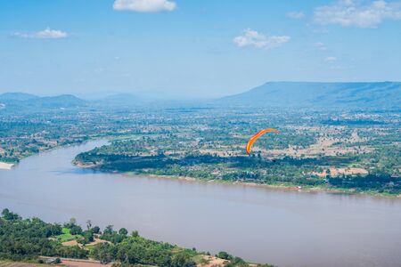 Person practicing paragliding flying sport over the Mekong River, outdoor adventure