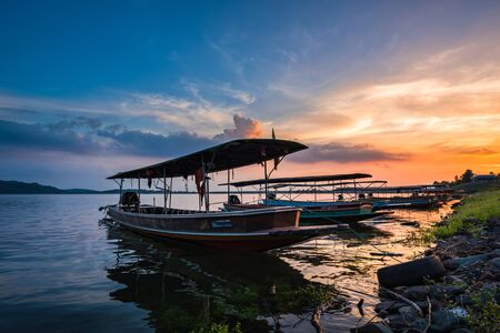 Passenger boats for tourism are parked in the river on sunset background at Khun Dan Prakan Chon Dam, Nakhon Nayok Province, Thailandの写真素材