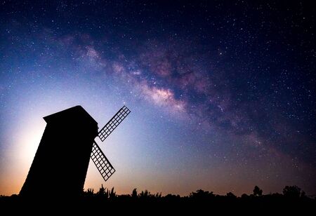 Landscape of milky way galaxy with wind turbine, Night sky with stars and silhouette of wind turbine and treeの写真素材
