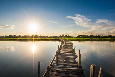 Long wooden bridge across the lake on sunset background at Kae Dam District, Maha Sarakham Province, Thailandの写真素材