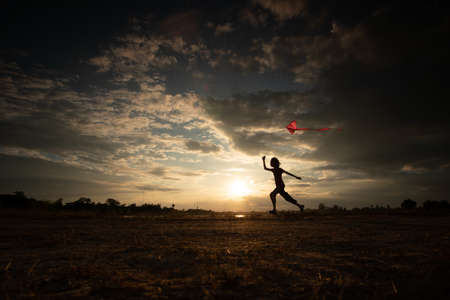 Silhouette of children flying a kite on sunset background invoke childhood memories