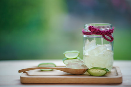 fresh aloe vera leaves and aloe vera juice in glass on wooden plate blurred nature backgroundの写真素材