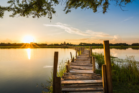 Long wooden bridge across the lake on sunset background at Kae Dam District, Maha Sarakham Province, Thailandの写真素材