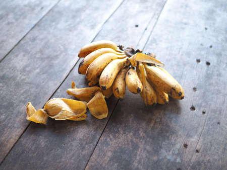 a comb of banana ripe golden yellow on the wooden floor 
banana peelの写真素材