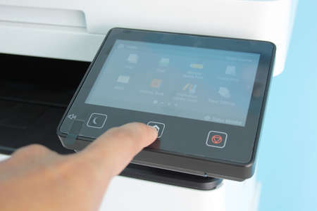Closeup hand press button to using the photocopier or machine is office work tool printer equipment...