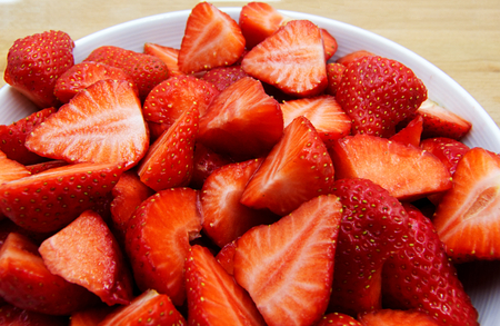 Sliced strawberries on a white plateの写真素材