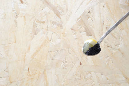 spoon with black lumpfish eggs, decorated with lemon from above, large copy spaceの写真素材