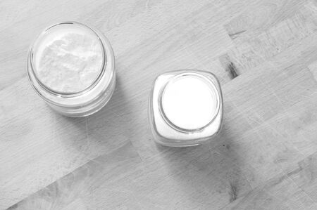 Two glass jars raised from above with sugar and flour on the wooden kitchen tableの写真素材