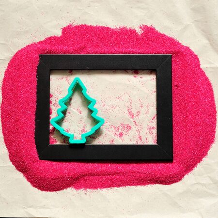 Christmas tree shape in a black frame, surrounded by red sand, squareの写真素材