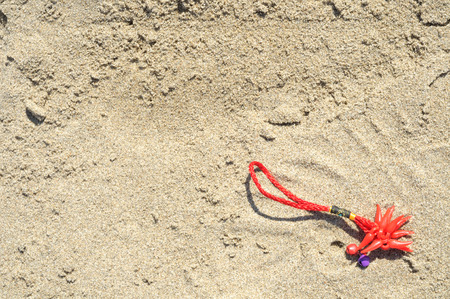 red bracelet lucky charm lost on the beachの写真素材