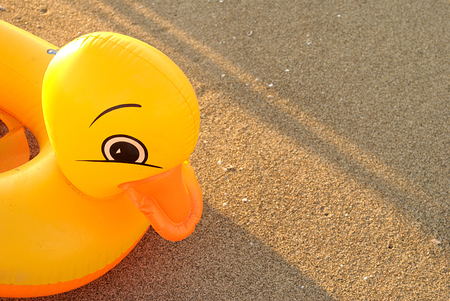 summer sea, yellow lifebuoy for children in the shape of a little duck on the sandの写真素材