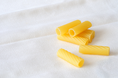 Itallian pasta, raw rigatoni on a white textured background with large room textの写真素材