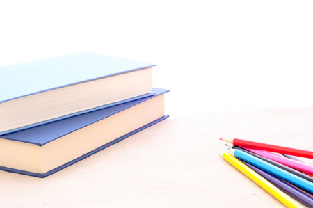pile of books and colorful pencils on white, minimal background, concept for school, learning, study