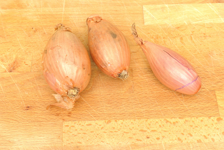 three shallots on wooden table, directly above, natural lightの写真素材