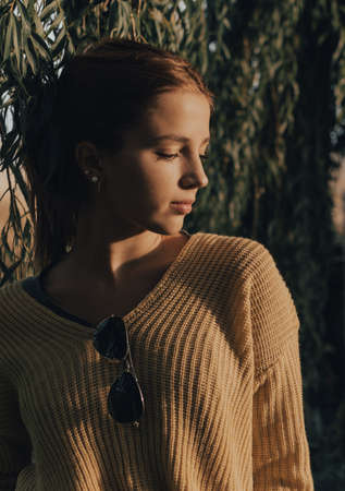 beautiful young girl with yellow sweater looking to one side at sunset.の写真素材
