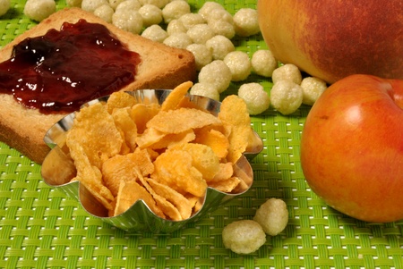 a full breakfast served on a green tablecloth with toast, jam, butter, cheese, peaches, plums,...