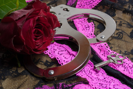 a pair of handcuffs with a red rose for the ladyの写真素材