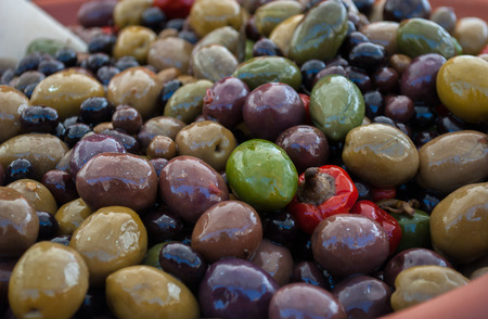 at a street market are selling green and black olivesの写真素材
