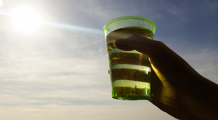 A glass raised in front of the sun godの写真素材