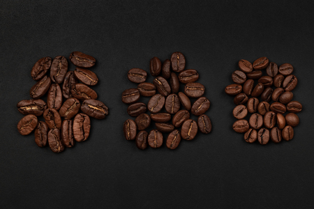 Roasted coffee beans piles from top on black backgroundの写真素材