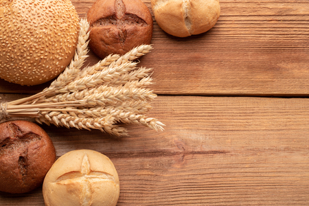 Fresh bread and wheat on wooden table. Top view with space for your text.の写真素材