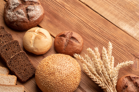 Fresh bread and wheat on wooden table. Top view with space for your textの写真素材