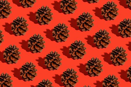 Minimal christmas composition. Pattern made of pine cones on red background. Christmas, winter, new year concept.の写真素材