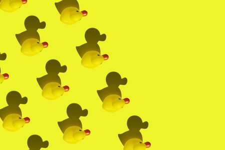 Yellow rubber duck pattern on neon yellow background. Place for text.の写真素材