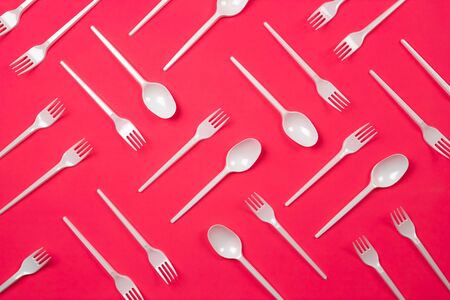 Pattern from plastic cutlery, forks, spoons. Pollution of the environment with plastic. Neon pink background. Flat lay style.の写真素材