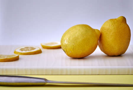 Several yellow sliced and whole lemons placed on a board with a light backgroundの写真素材