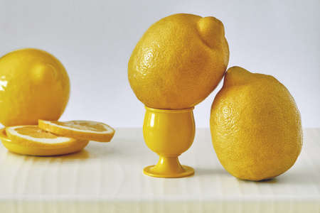 Several yellow sliced and whole lemons placed on a board with a light backgroundの写真素材