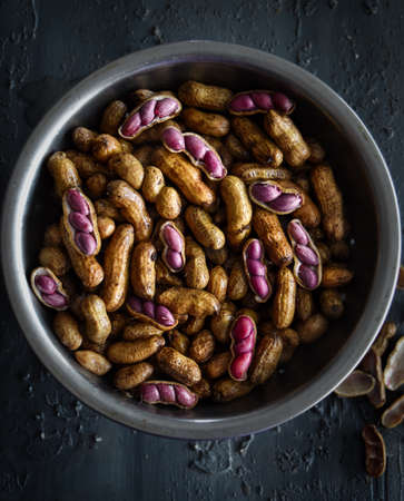 Close-up and macro shot of fresh boiled peanuts in a bowl, some shelled and with visible pink peanutsの写真素材