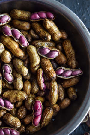 Fresh boiled peanuts in a bowl, some shelled and with visible pink peanutsの写真素材