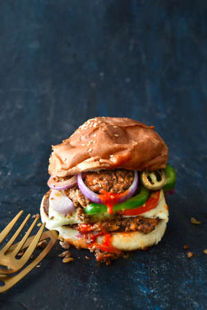 Vegetarian Bean Burger with chili sauce, onions, tomato and bell pepper. Restaurant concept foodの写真素材
