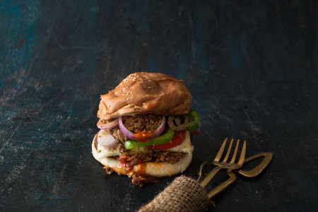 Vegetarian Bean Burger with chili sauce, onions, tomato and bell pepper. Restaurant concept foodの写真素材