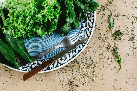 delicious fresh salad arugula spinach on amazing plate and cutlery on craft background, space for textの写真素材