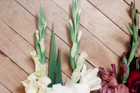 beautiful gladiolus in different colors flowers on wooden rustic background, arrangement concept, amazing wallpaperの写真素材