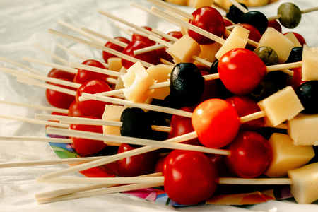 cherry tomatoes olives cheese on wooden stick appetizer, picnic outdoors, catering buffet at summer celebrationの写真素材