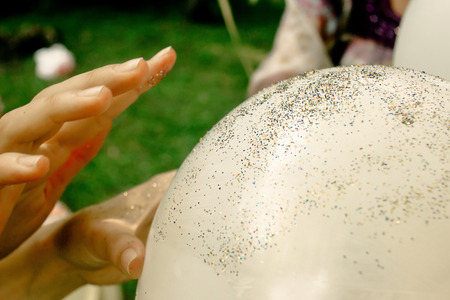 woman hands decorating white big balloons with sparkles glitter outdoors, adorning and arrangement at celebration events, bridal showerの写真素材