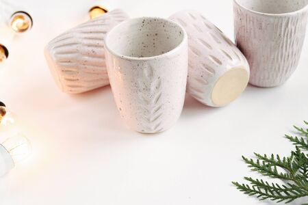 stylish creative ceramics cups and christmas garland lights, holiday celebration conceptの写真素材