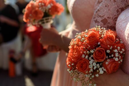 stylish bridesmaids in pink lace dress holding amazing bouquets of roses at wedding ceremonyの写真素材