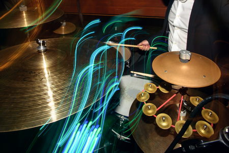 stylish drummer playing on a drums with a band on wedding reception with cool motion lightの写真素材