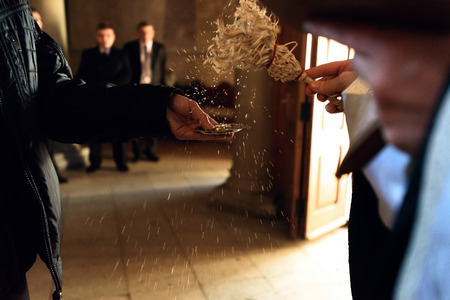 golden wedding rings on plate in priest hand at traditional ceremony in church, getting blessedの写真素材